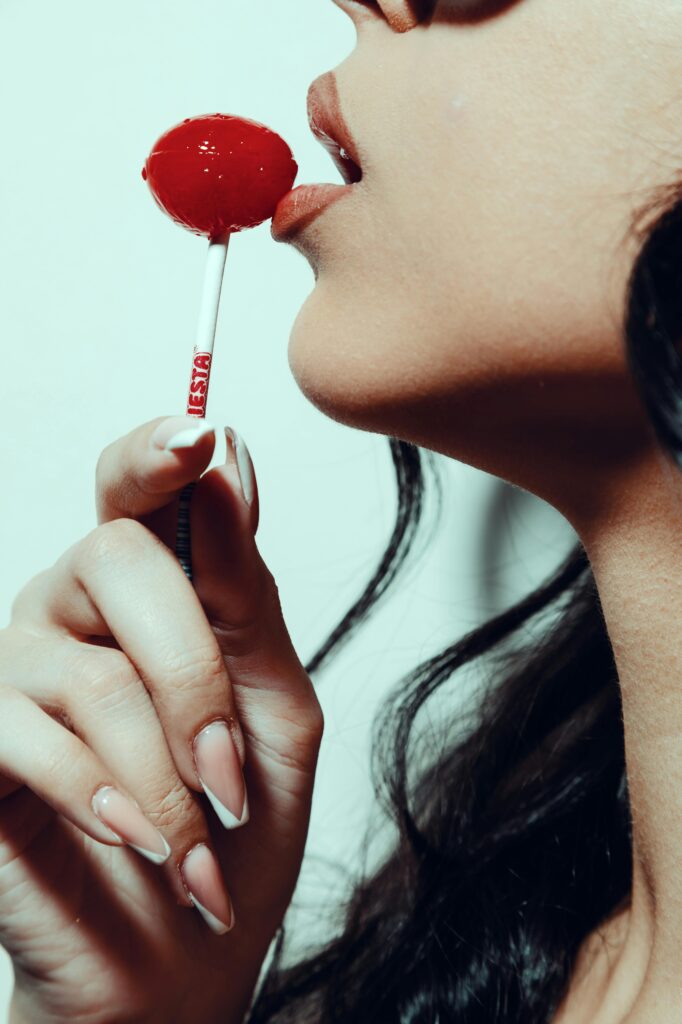 A close-up shot of a woman enjoying a red lollipop, highlighting details.