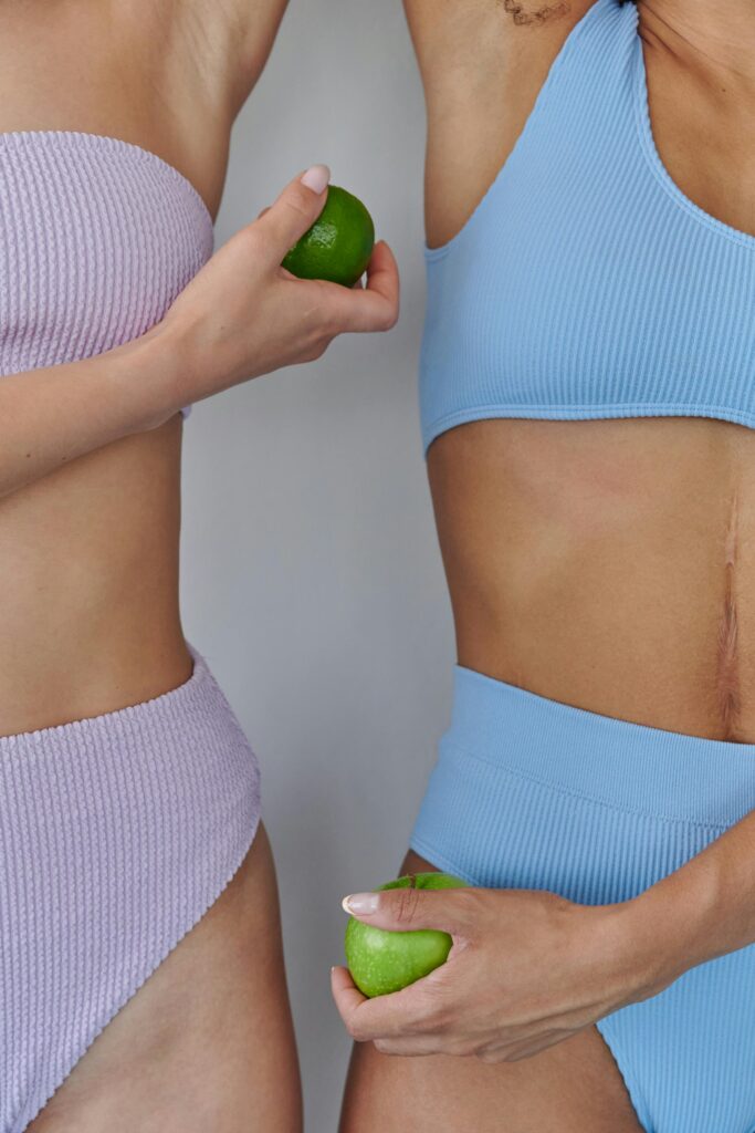 Two women in pastel swimwear holding limes on a white background.