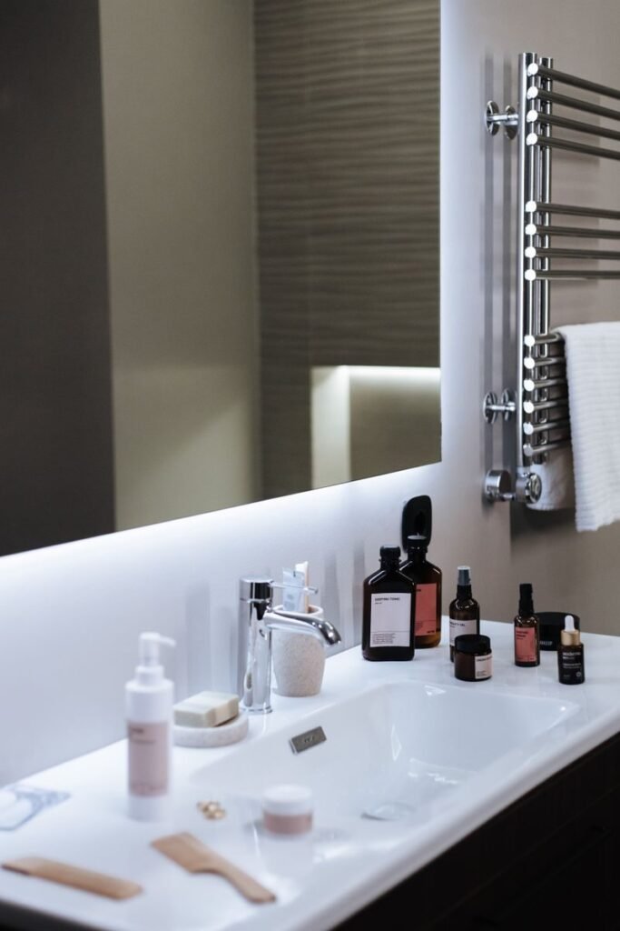 Elegant bathroom sink setup with cosmetics and mirror, offering modern aesthetic and copy space.